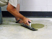 Repairing the cored holes in the concrete slab floor with fresh concrete and cleaning up the Rome home.