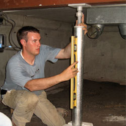 A contractor in Auburn installing a crawl space jack post.