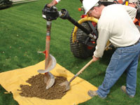Auguring a hole in the earth for a foundation wall repair system in Rome