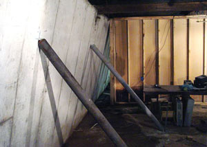 A severely tilting foundation wall propped up by steel beams in Massena.
