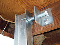 Securing the i-beam system to the top of the floor joist in a foundation wall repair in Rome.