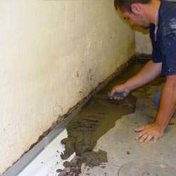 A basement waterproofer installing a perimeter drain system in Baldwinsville
