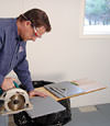 installing a waterproof vapor barrier on a basement floor to prepare for basement carpeting in a Ithaca home